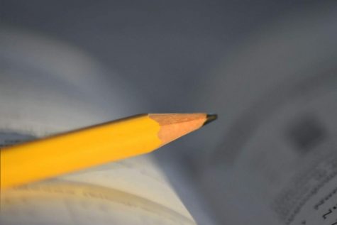 A pencil sits on a book while a student works