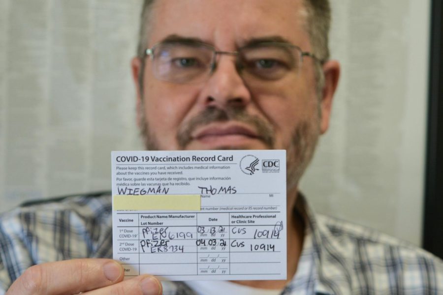 English teacher Tom Wiegman holds up the COVID-19 Vaccination Record Card he received after being vaccinated with the first dose of the Pfizer vaccine in March 2021 and the second dose in April 2021. The Fullerton Joint Union High School District [FJUHSD] sent out an email Sept. 2 to all staff mandating vaccination verification to fulfill a state requirement that the governor signed into law Aug. 11. Anyone working in the FJUHSD who chooses not to be vaccinated must take a COVID-19 test on a weekly basis beginning Oct. 18.