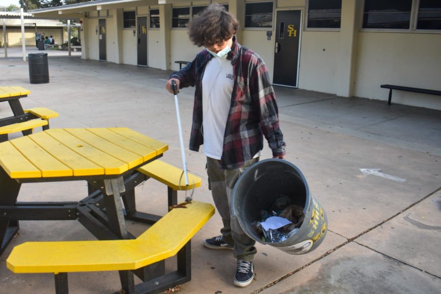 With+a+trash+picker+in+his+right+hand+and+a+trash+container+in+the+other%2C+sophomore+Adrian+Ramirez+demonstrates+on+Tuesday+how+he+helps+out+after+school.+