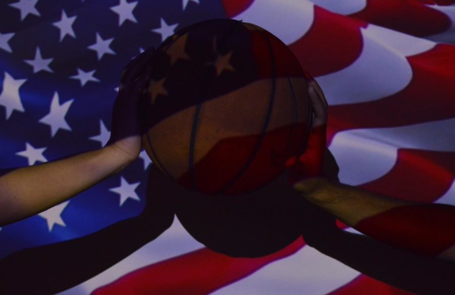 Two people hold a basketball with a projected American flag.