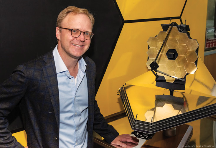 Here, McElwain stands next to a small prototype of the James Webb Space Telescope. McElwain continues to be an integral part of the project by leading the science component of the post-launch assessment review.