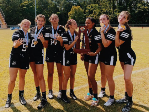 (From left to right) Seniors Haley Magin, Ava Hogan, Brianna Stearns, Jaylen Stasio, Sydney Hall, Lindsey Chadwick and Casey Ingram pose with the FHSAA Flag Football Class 1A State Championships trophy and their gold medals.
