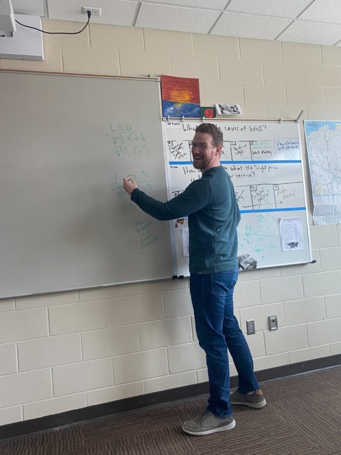 Social studies teacher Nicholas Covington poses against the whiteboard in his classroom after writing down notes for his economics class. Covington said that it was tough to tell everyone he was leaving, but glad they all understood.

 “That was the hardest part I think, telling the students because there were audible gasps,” Covington said. 