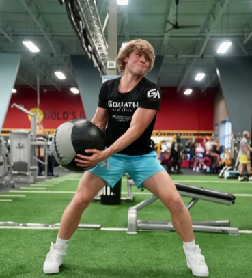 Newquist does an exercise in the gym while modeling a Goliath Athletics shirt and shorts.