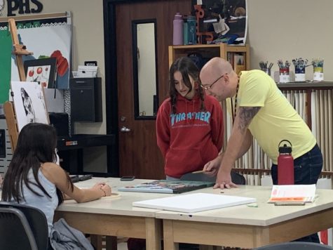 Leaning over the desk, art teacher Andrew Scott advises junior Noa Maddock on what to do next with her piece in her AP 2D Design portfolio. Students in AP art classes create a sustained investigation, building every piece of art off of their previous meaning. He gives helpful criticism, Maddock said. In showing how to progress my work further. 