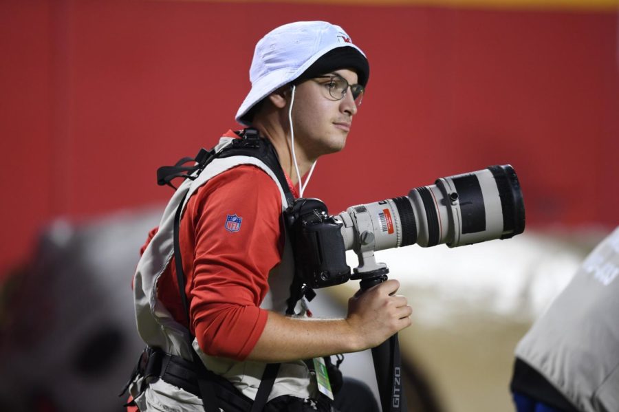 Camera in hand, photographer Ben Green prepares to shoot a National Football League (NFL) game. Green works as the team photographer for the Buffalo Bills.