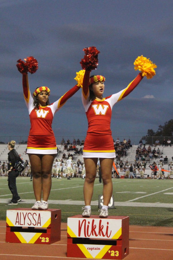 Alyssa Smith and Nikki Nguyen cheer together for the
Woodbridge football team from the sidelines.