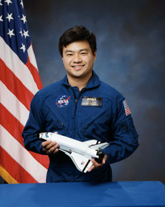 American astronaut Leroy Chiao poses with a model space shuttle for an official NASA portrait. During his fifteen-year career with NASA, he completed four space missions.
