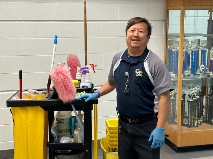 Ocean Lakes’ Custodian, Chi Ha, smiles out in the hallway on Jan. 27, 2023. 