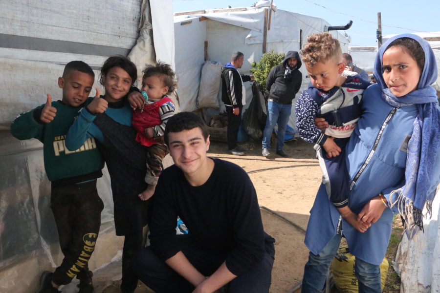 Bassel Ojjeh (’25) poses with those affected by the Turkey-Syria earthquake in a camp located in western Syria. Ojjeh founded H.O.P.E Syria, a charity  providing education to children and assisting refugees amid the humanitarian crisis. 