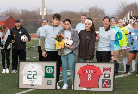 From left to right: Jack Elking, Lydia Elkings mother Kerry, Dani Elking and coach Kleekamp stand with Lydias framed St. Louis Scott Gallagher and Liberty jerseys.