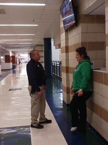 Steve Aspinall, school resource officer, talks with Kasey Mills, hall monitor, while he ensures safety in the halls. Four resource officers were hired to increase officer coverage at the elementary schools.