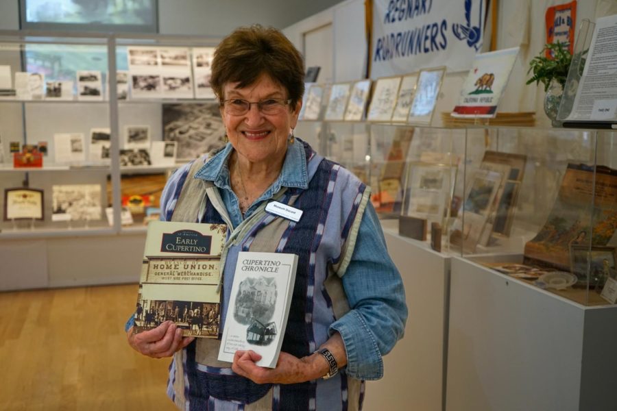 Gail Fretwell-Hugger stands in the Cupertino Historical Museum holding two books about Cupertinos history. Photo by Alan Tai