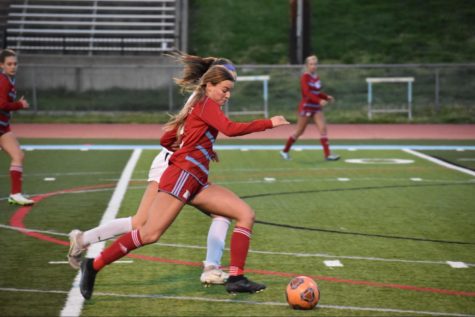 Lunging for the ball, senior Julia Liguore looks for a pass. Liguore was a starter and team captain of the varsity soccer team. “[My favorite thing about] high school soccer is getting to play in a stadium, getting [my] name called out and running out through the [player] tunnel,” Liguore said.