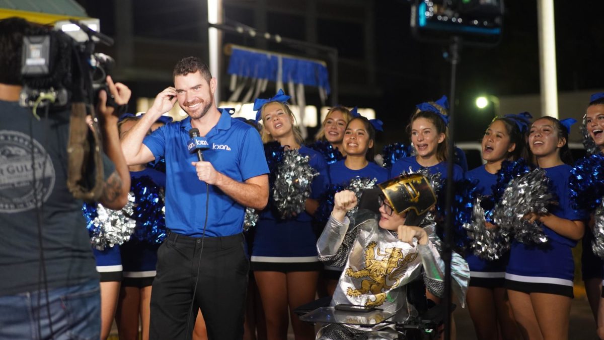 Junior Ben Polega and the cheer team appear in front of Taco Sack during the KXAN live broadcast announcement of the spirit competition winner. 