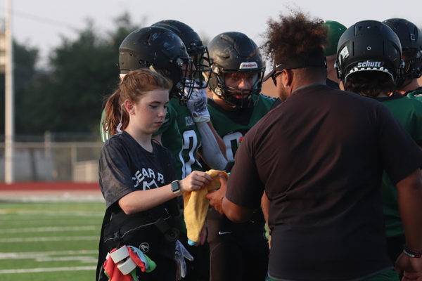 Handing a towel to a coach, freshman Norah Goett  fulfills her duties as an athletic trainer at the JV game against Vandegrift on August 31. As a part of being a student trainer, Goett is required to go to every football practice and game. I enjoy the fun of helping people,” Goett said. “Being able to go to the games and be on the field and have that experience is really cool.”
Photo by Alyssa Fox