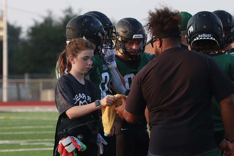 Handing+a+towel+to+a+coach%2C+freshman+Norah+Goett++fulfills+her+duties+as+an+athletic+trainer+at+the+JV+game+against+Vandegrift+on+August+31.+As+a+part+of+being+a+student+trainer%2C+Goett+is+required+to+go+to+every+football+practice+and+game.+I+enjoy+the+fun+of+helping+people%2C%E2%80%9D+Goett+said.+%E2%80%9CBeing+able+to+go+to+the+games+and+be+on+the+field+and+have+that+experience+is+really+cool.%E2%80%9D%0APhoto+by+Alyssa+Fox