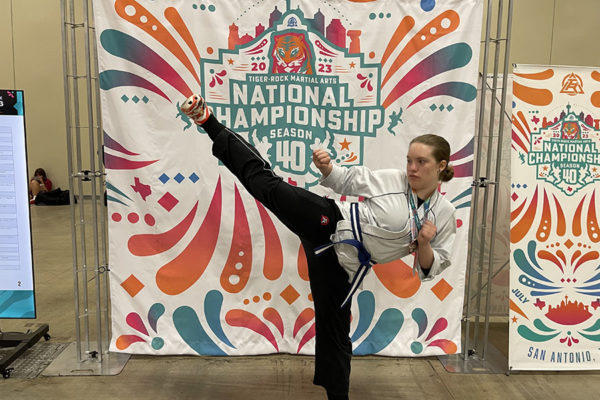 Striking a pose in front of the Tiger-Rock Martial Arts National Championship banner, junior Brooklyn Collinsworth shows off her flexibility and blue belt. The tournament was held at the Henry B. González Convention Center in San Antonio from July 20-23. “I end[ed] up getting bronze in the overall board breaking competition,” Collinsworth said. “My opponents were much older and had a lot more experience.”
