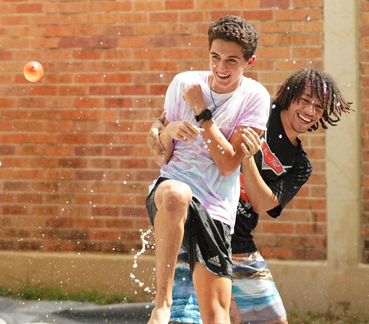 WATER BALLOONS AND SMILES: Senior Peer Assistance and Leadership program member Jude Masoni holds up his fellow PAL, senior David Herring, as a human shield to protect himself from the path of an incoming water balloon. Students paid  to throw a balloon at the PALS on Tuesday as part of the shooting PAL-ery, one of the Pink Week fundraisers intended to raise money for the Breast Cancer Resource Center of Central Texas, an Austin-based non-profit that provides personalized support to those affected by breast cancer.  Year after year the PALS put on Pink Week in order to raise funds and awareness for the fight against breast cancer. The PALS put on a variety of different events the whole week at lunch in hopes of both bringing in profits and bringing an exciting week of fun to the McCallum community.   

Herring was made a target of the water balloon by his cross country teammates.

“I enjoyed seeing my teammates coming out to donate as I was telling them about it the week prior,” Herring said. “I was also just having fun on that nice day with my fellow PALS. Some of them that did the pallery that day, like Jude, I’ve known since elementary school.”

Caption by Chloe Lewcock with reporting by JoJo Barnard.  