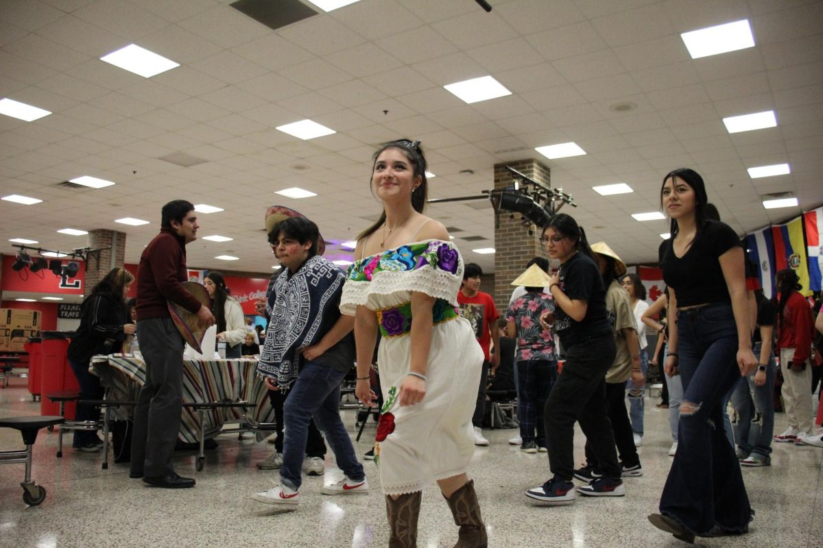 During 8th grade orientation, graduate Luna Tafolla dances with the Spanish Club. Behind her are some of the many flags in the cafeteria that represent the countries that students at LHS come from.
