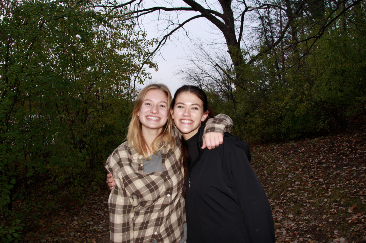 Seniors Cady Peterson and Vivian Marchan pose near the Lakeside Plot where they spent many hours over the last two years collecting data. Both students frequently wore chest-high waders and crawled under branches and shrubbery to count buckthorn stems. “Im really thankful that I had someone as amazing as Cady to do research with,” Marchan said.