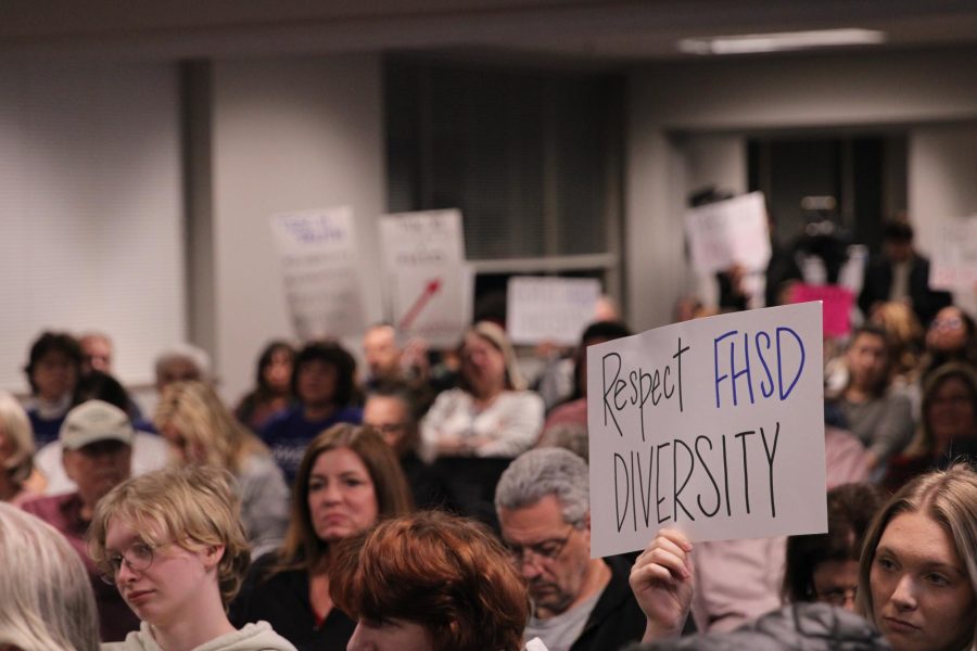 Members of the Francis Howell community hold up signs of disapproval towards the school board at the Dec. 21 board of education meeting.