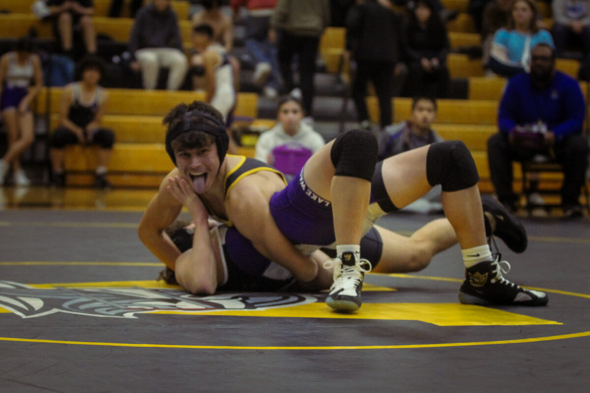 Jaden+Perez+poses+for+the+camera+as+he+pins+his+opponent+in+a+half-nelson.+