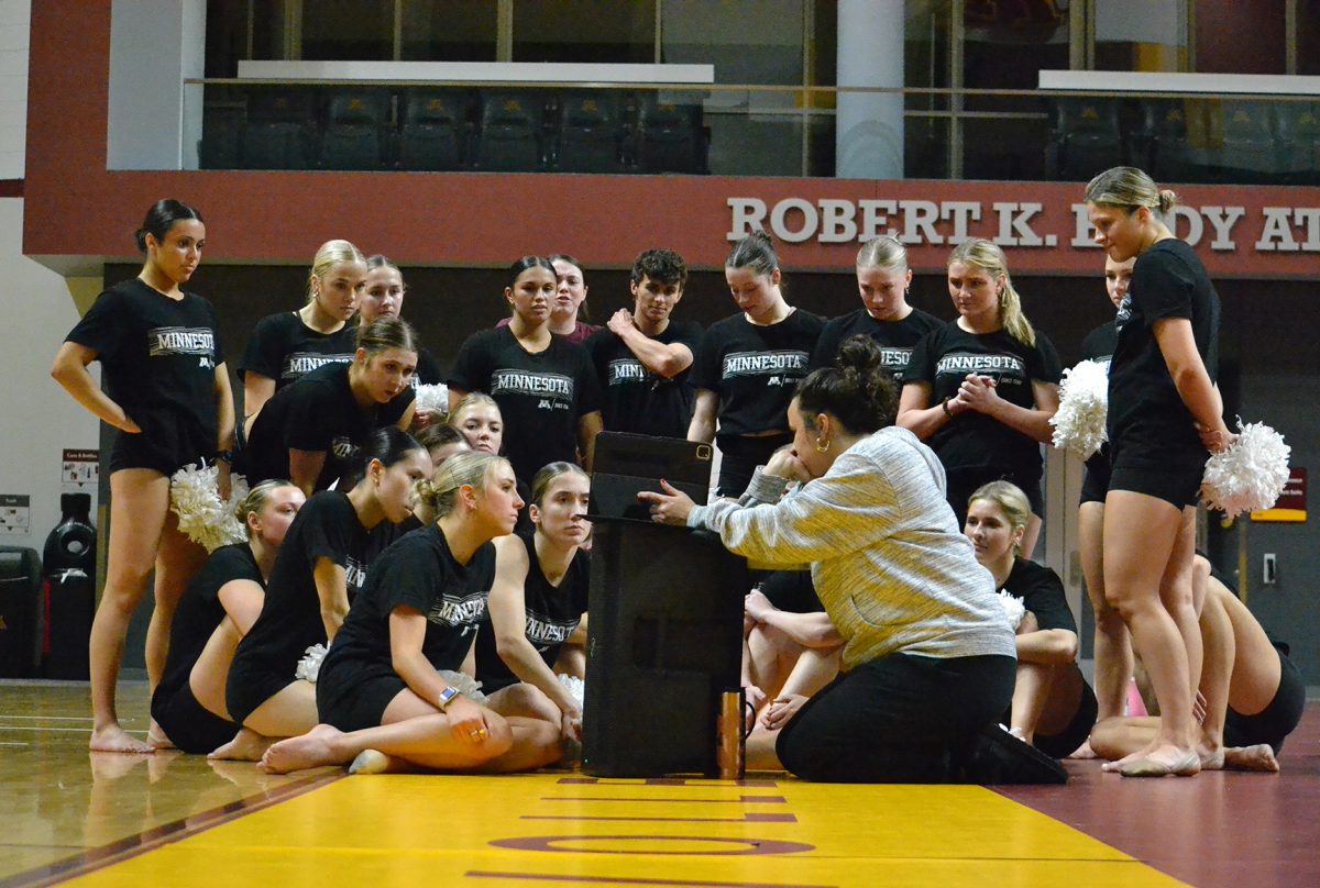 University of Minnesota Dance Team huddles around their Assistant Coach Tia Tumbleson as they watch the video of their routine at practice on Nov. 4, 2023. The team uses video to fix any inconsistencies that come up in the routine.