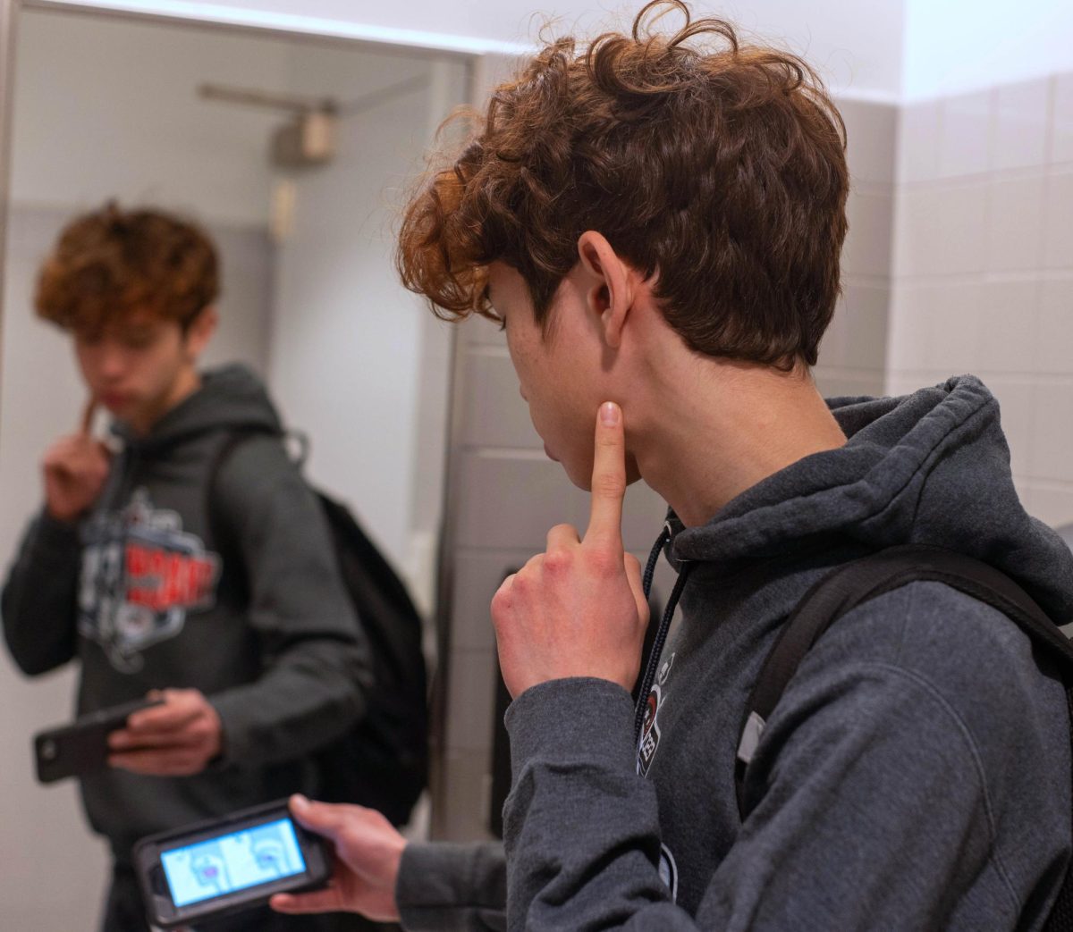 A student looks at his phone, following a  tutorial for a looksmaxxing method, mewing. Recently, looksmaxxing has risen in popularity on the internet and at U-High.