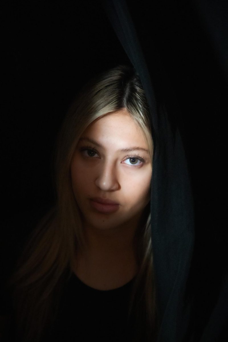 Junior Giselle Yokomichi poses behind a curtain. For Yokomichi, her experience with sexual assault was a battle between sharing her story and staying quiet. "As far as my own experience and others, a lot of the time you want to stay anonymous and we want to keep the other person anonymous," Yokomichi said. "You don't want to be reminded of it. I feel like most victims want to stay quiet and hidden away."