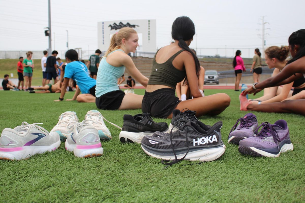 Zoe Martin, senior, and Anishka 
Bhatia, senior, stretch after cross country practice. Hoka and Brooks shoes are popular among runners.