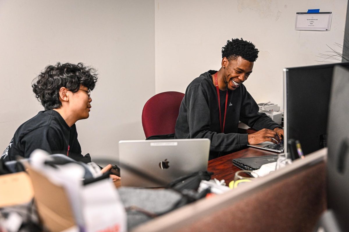 Junior varsity basketball coach Xavier Smith shares a laugh with senior Joonsung Kim in his office located in the Information Services department.