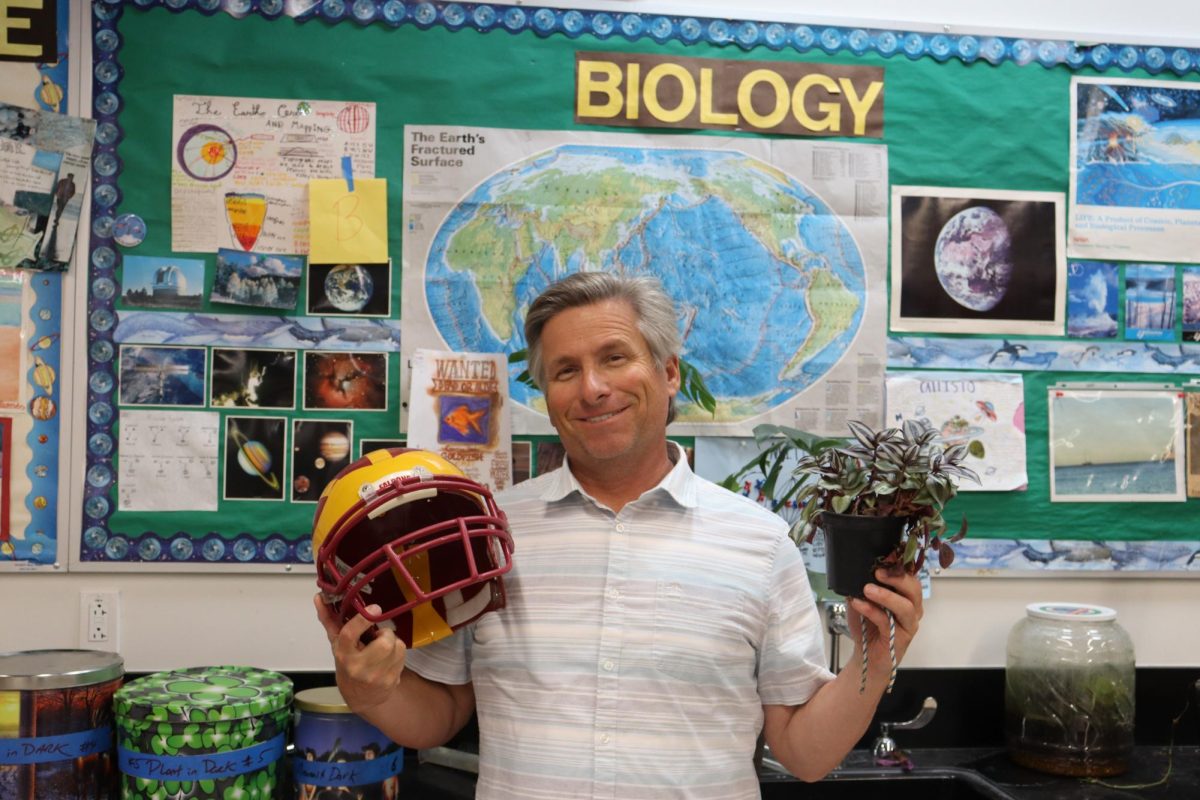 Biology and football P.E. teacher Matthew Livingston holds a football helmet in one hand and a potted plant in the other. Livingston began teaching biology 29 years ago, and spent the last six years teaching Year 1 P.E. or football P.E. simultaneously.