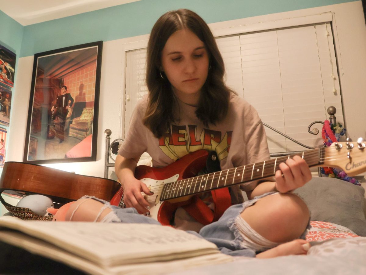 Coppell High School junior Alyssa Gray strums the melody to “Snowman” by Sia on her electric guitar in her room on Dec. 11. Gray loves music from the 1950s and 1960s, introduced by her father, Adam Gray. (Photo by Caitlyn Conception)