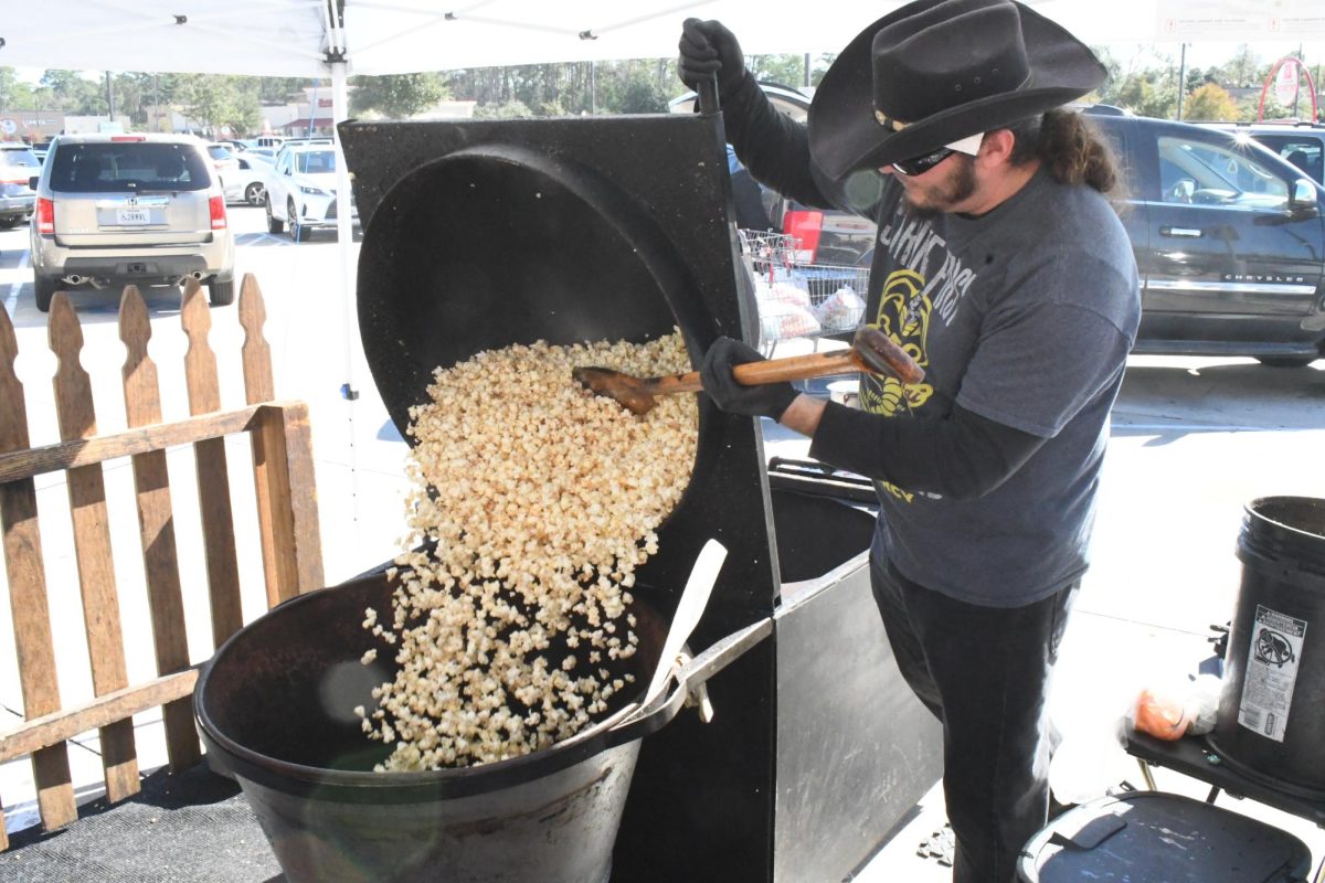 Jake Garza transfers kettle corn that is ready to be packaged up for customers in the H-E-B parking lot off Kingwood Drive. Garza used to help in his father’s kettle corn stand, and now his kids help him. 