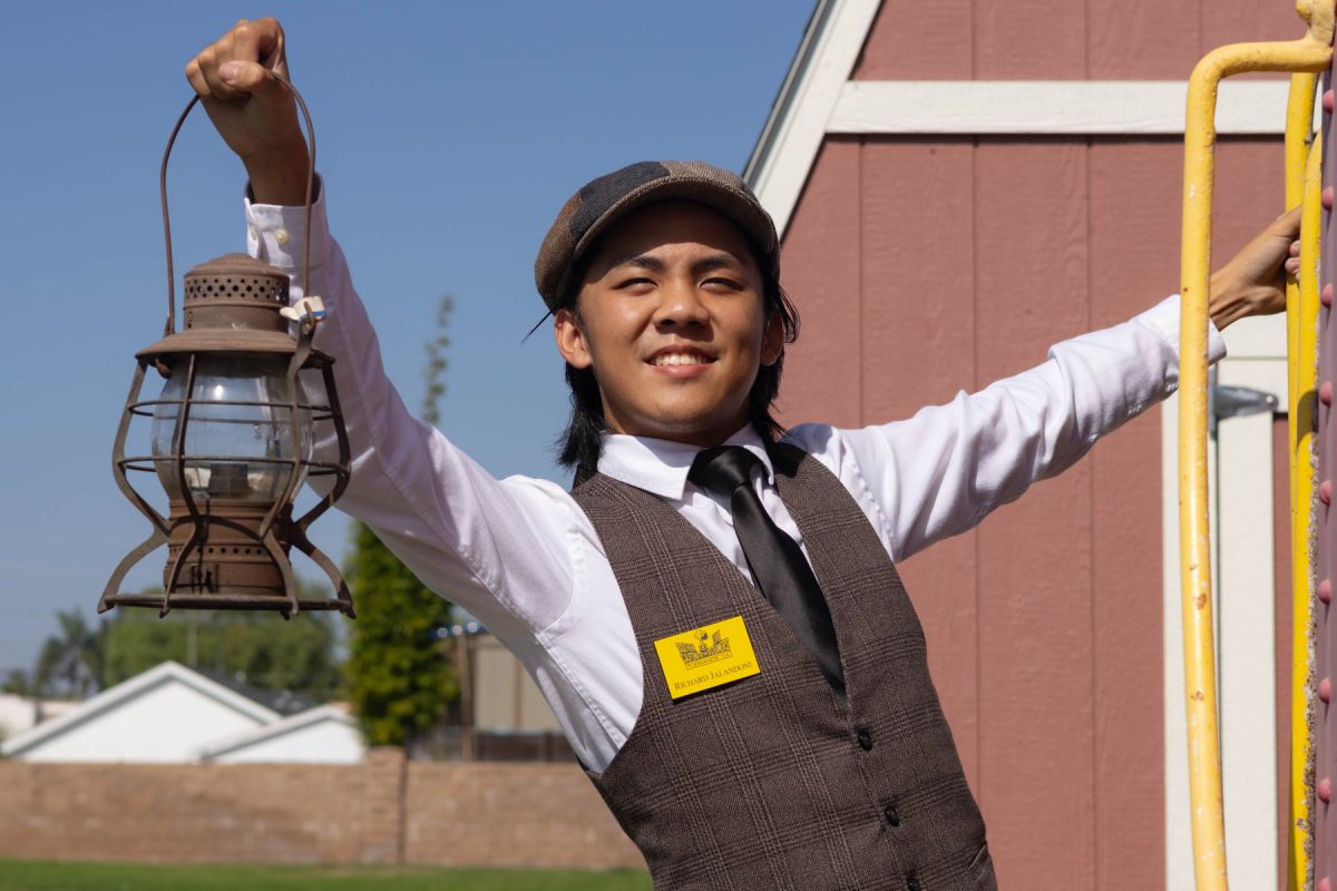 Richard Soriano Jaladoni, 18, hangs off a Southern Pacific caboose at the Lomita Railroad Museum on Oct. 13. Jaladoni holds a signal lap, which was used by railroad workers to communicate at night. The museum has a collection of several examples. (Katie Gronenthal | Warrior Life)