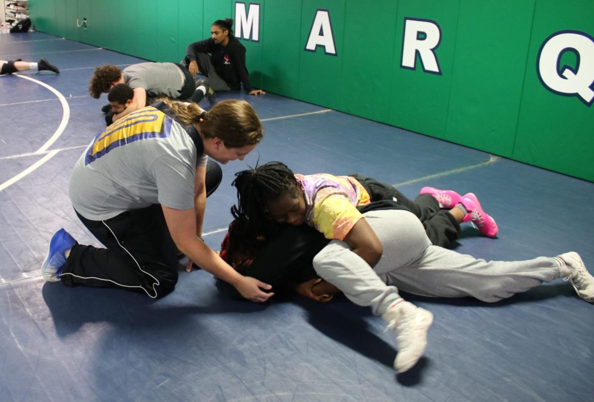 Kristi Rutsch, wrestling coach, gives pointers to Malaysia Hunt, junior, and Honesty Smallwood, freshman, at an after school practice on Tuesday, Dec. 3. Rutsch is one of the new  wrestling coaches during this year's season. 