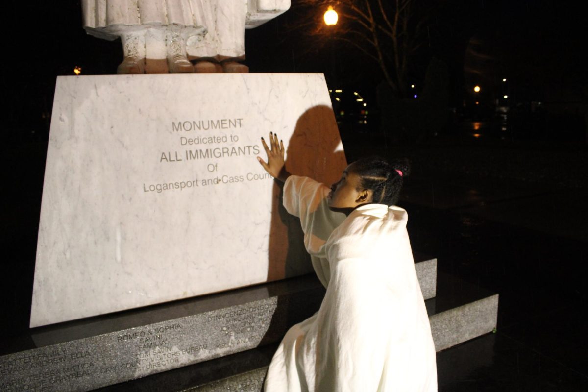 Haitian student Lauryn Aubuin stands next to the Immigrant Statue in downtown Logansport. 