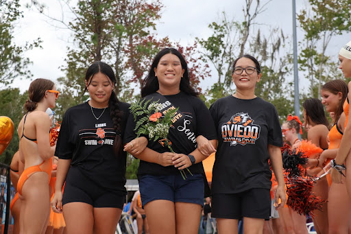 Anne Shuai walks down the aisle of her teammates, accompanied by her mom and sister, on her senior night swim meet. 