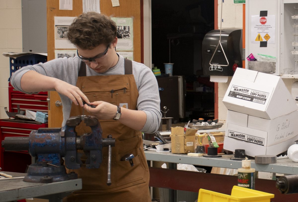 Senior Ben Kahn works in the Robotics Club workshop. In the process called tapping, Kahn create holes in workpieces for the robots.