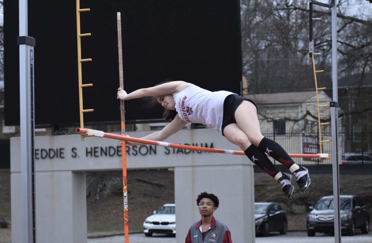 Junior Nadia Jurkovic clears the bar during the pole vault event in the Midtown Opener on Feb. 27 2024 as junior Elijah Huffman looks on. Under the changes to the spring sports start date, spring sports like track and field and soccer are not allowed to practice as a team using equipment like poles until Jan. 27 instead of Jan. 8 like previous years.