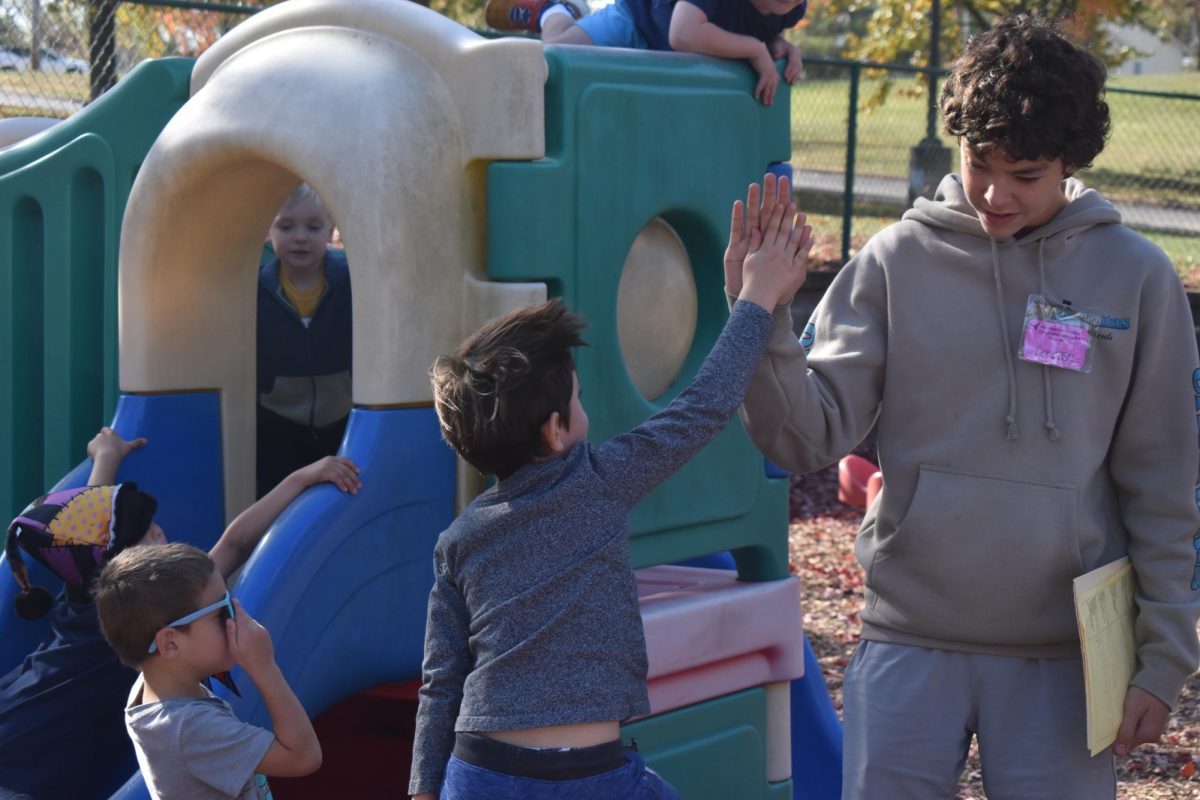 Raising his arm for a high five, freshman Abram Brazier plays with Early Childhood Center students during his first visit of the semester. Brazier joined his assigned class during their designated outdoor time. “[Child Development] gives me experience with how to talk [to] kids. We read them a book so knowing how to talk to them [was helpful]. Most of the [preschoolers] just came right up to us [and] played around,” Brazier said. 