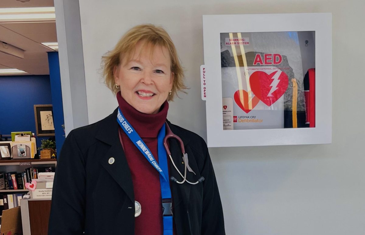 Nonnewaug school nurse Sandy Snabaitis poses next to one of the six AEDs at Nonnewaug.