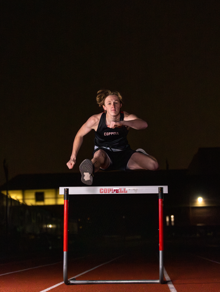 Coppell junior track and field athlete Noah Schuller hurdles before sunrise on Jan. 28 at Buddy Echols Field. Coppell High School’s thriving sports culture is driven by the dedication of student athletes and their pursuit of victory. Photo by Kayla Nguyen.