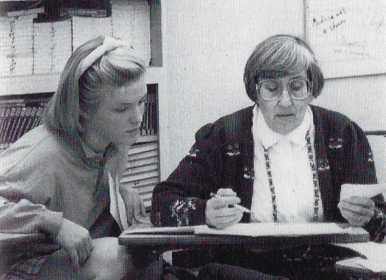 Carol Hallenbeck (right), who taught journalism and advised The Accolade school newspaper from 1969-1993, scans a paper with a pencil in her right hand while a staff member observes. Hallenbeck died of old age Sunday, Feb. 2, in her Costa Mesa apartment. She was 97.