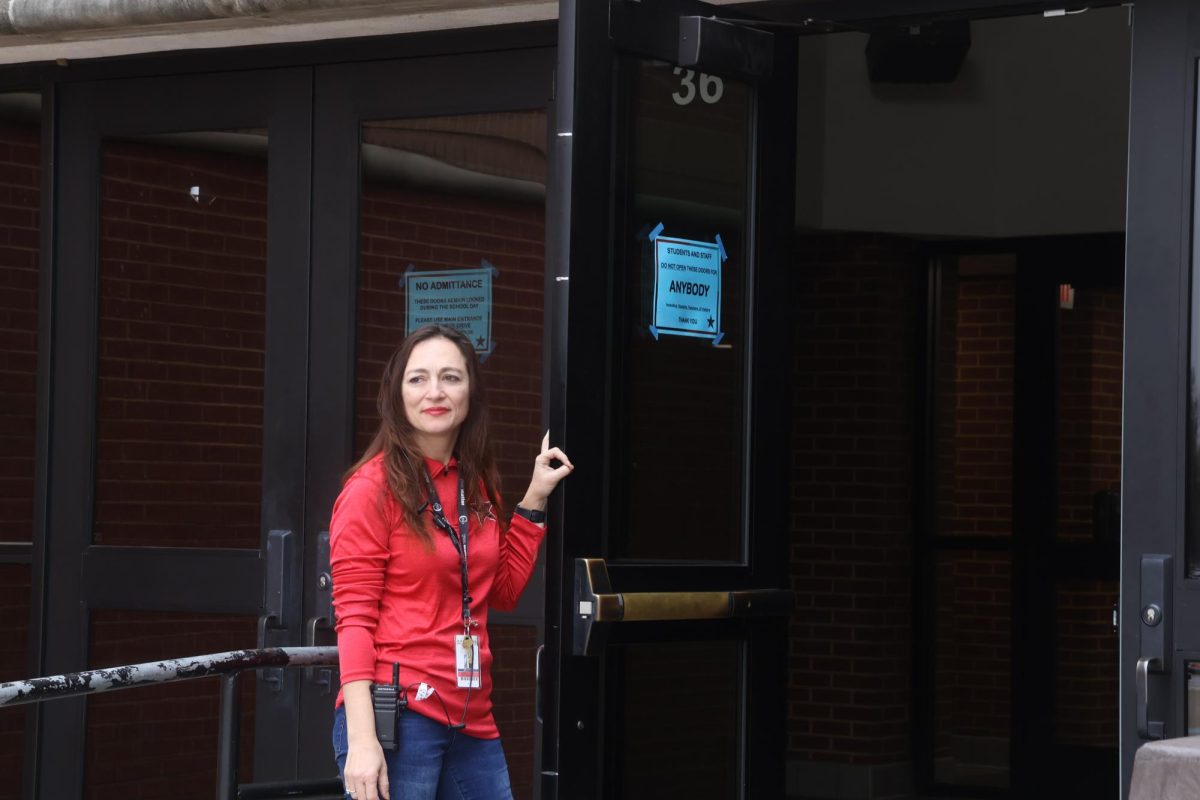 Coppell High School security attendant Liza Petrova holds the door open at the north entrance for students arriving in the morning on March 7. Petrova fosters a welcoming and supportive atmosphere for students through her friendly interactions.