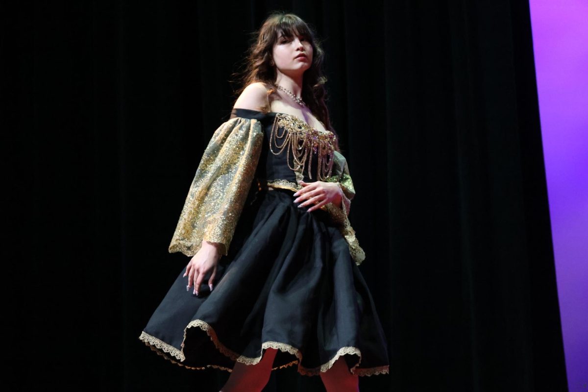 Posing, senior, designer and model Jade Hotard showcases one of her designs as she walks down the runway. At the fashion show, designers were able to create three pieces that matched the theme of fantasy. “It's based off of the Black Swan from the ballet Swan Lake,” Hotard said. “It came to me in a dream, and I was like, I need to make this dress.”
