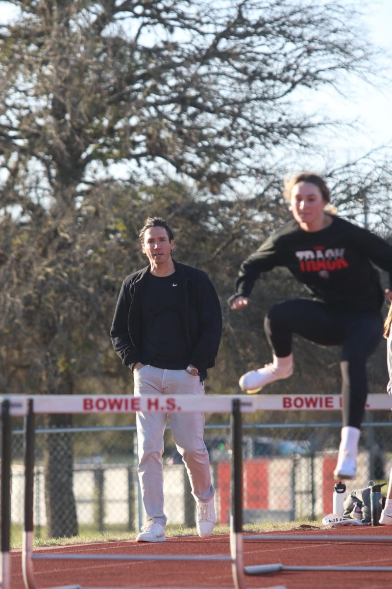  Hamza Deyaf yells instructions and encouragement as Bowie track member Emelia Lynn runs hurdle drills. Deyaf learned to skills necessary to coach this event after running it for the University of Texas.