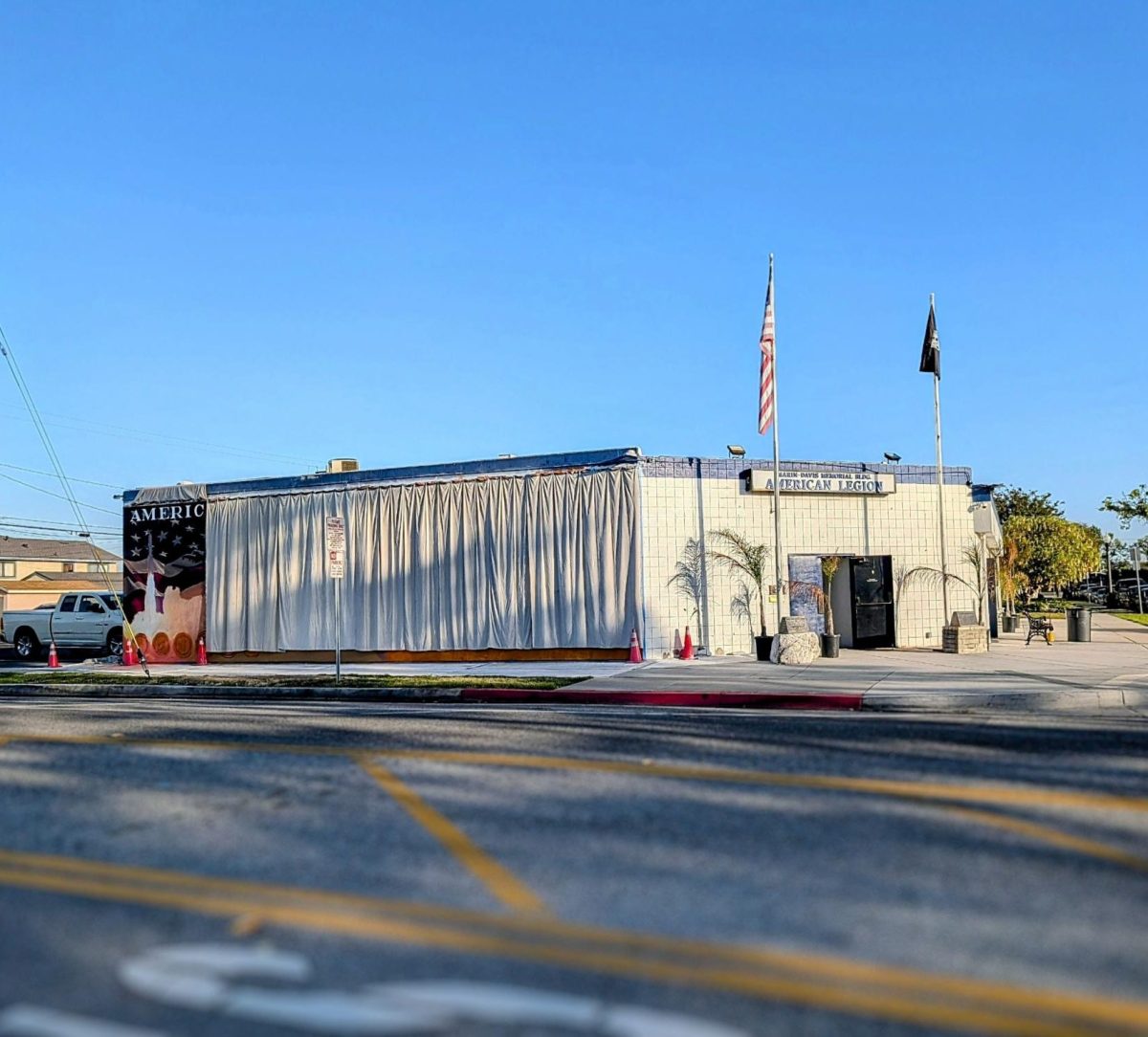 The American Legion Marin-Davis Post 716 building currently features a white curtain covering the in-progress mural, showing only a small portion of the grand art piece.