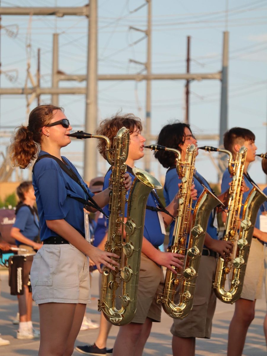 GRAND REVEAL: Sophomore Cruz Gonzales performs alongside the other baritone saxophone players during Bandapalooza on Aug 22. Bandapalooza allowed the band to perform what they’ve been practicing during the summer to an audience full of friends and family. 

While this wasn’t the band’s first full run through, it was their first in front of an audience. 

“I feel like we’ve done better in rehearsals, and due to the pressure and other things, it hindered our performance a little bit, but I was still proud,” Gonzales said.

One thing that Gonzales pointed out that the band needs to work on in the future is making sure everybody knows exactly where they’re supposed to be and knows the repetition. 

This performance also allowed the band to introduce their new theme of Gothic Renaissance to their audience. 

“This year’s costumes are totally different,” Gonzales said. “We have hip capes and shako hats, which is a big change from last year.” 

Looking towards the future and big pictures, Gonzales wants the band to have a successful season and make state.

“Considering how close it was last year, we were pretty bummed,” he said. “So this year, I think everybody is really trying to work harder to get there and make state again.”

Caption by Maya Tackett. Photo by Wren Vanderford.